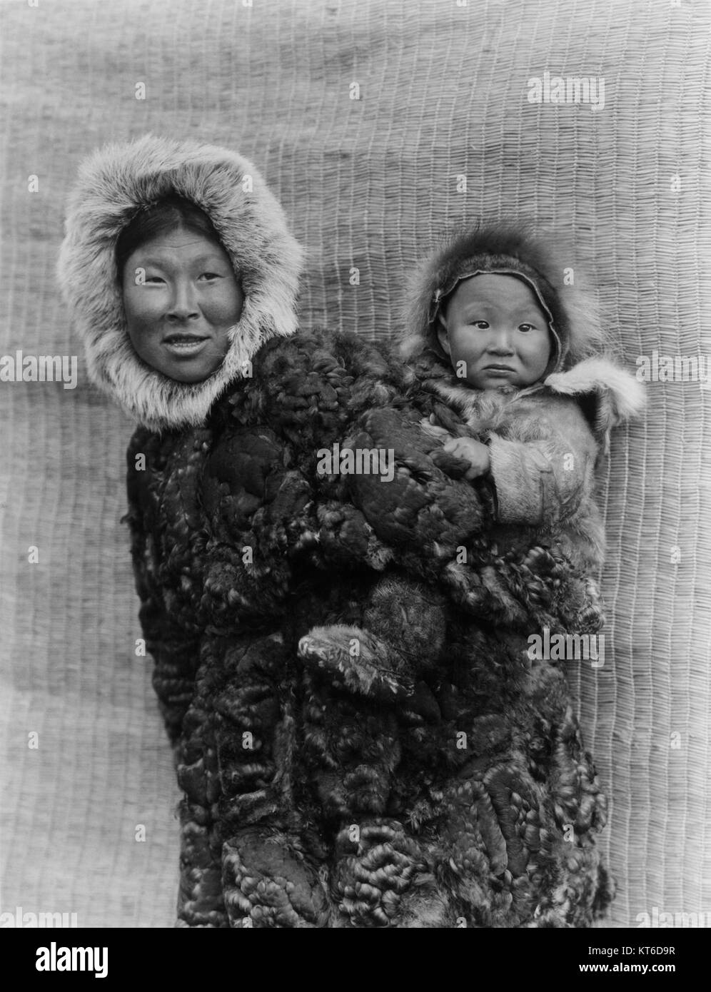 Questa fotografia restaurata di Edward S. Curtis cattura una donna e un bambino di Nunivak Island, Alaska. Curtis era noto per aver documentato le culture dei nativi americani e degli indigeni dell'Alaska all'inizio del XX secolo, preservando le loro tradizioni e il loro stile di vita attraverso la fotografia. Foto Stock
