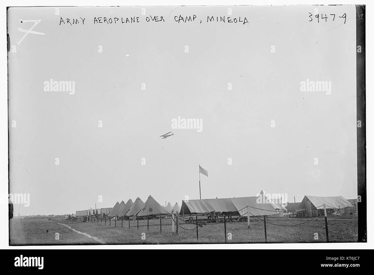 Questa immagine storica mostra un aereo dell'esercito che vola sopra un campo militare a Mineola, probabilmente tra l'inizio e la metà del XX secolo. La foto cattura l'aviazione militare e l'uso attivo di aeromobili in addestramento o operazioni militari. Foto Stock