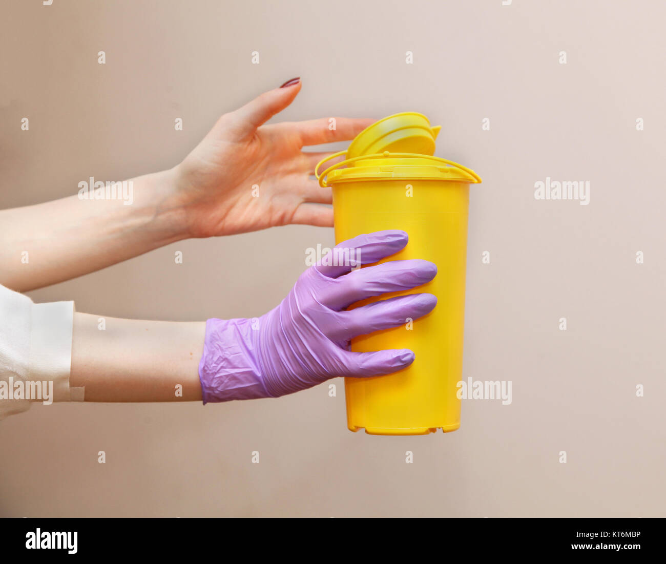 Medical contenitore di rifiuti in mani femminili con guanto chirurgico Foto Stock