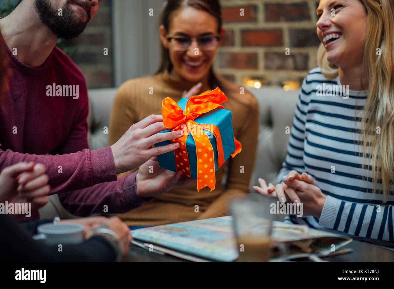 Immagine ravvicinata di un uomo che passa un regalo di compleanno per il suo amico alla sua festa di compleanno. Foto Stock