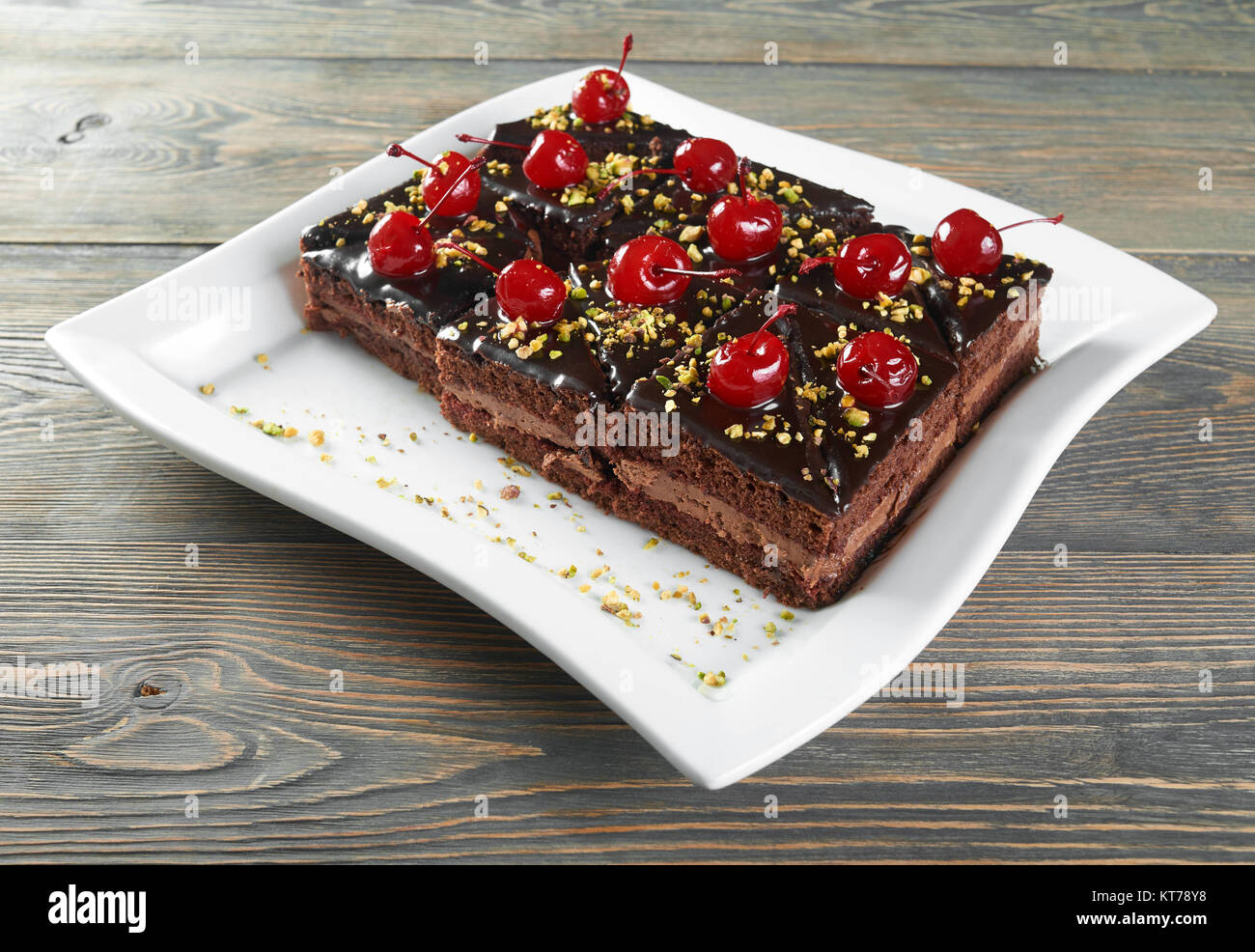 Una piastra bianca servita con una torta cremosa,coperto con la glassa al cioccolato e un delizioso cocktail ciliegie per una gustosa cena. Foto Stock