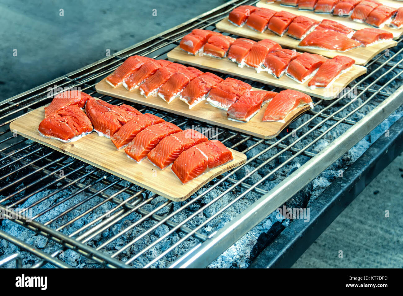Filetto di pesce rosso sulle linguette di legno su carboni ardenti, su una griglia Foto Stock