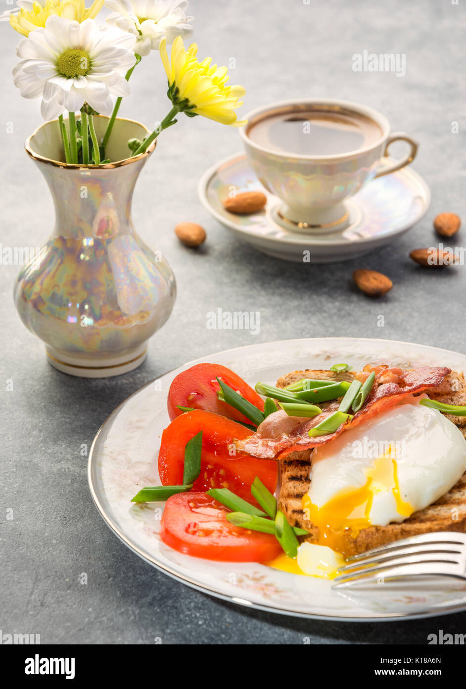 La prima colazione con uova in camicia, tostato, pancetta, pomodori e caffè Foto Stock