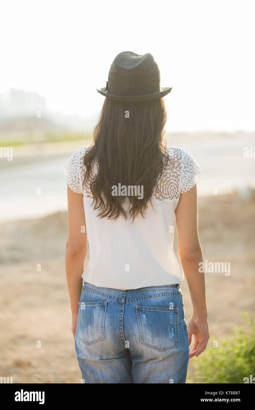 Vista posteriore di una giovane donna che indossa un cappello in piedi all'aperto Foto Stock