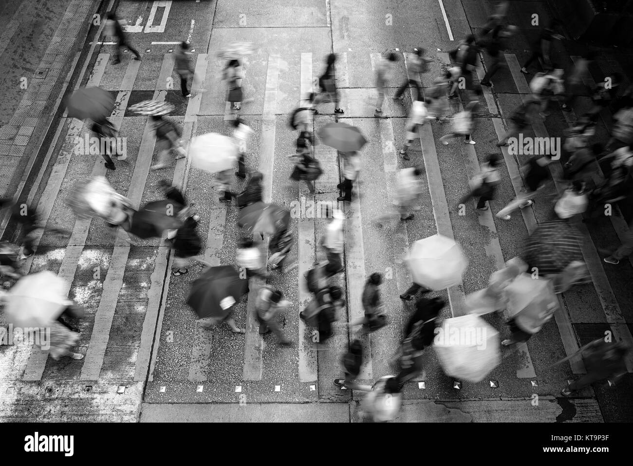 Il movimento sfocati pedoni che attraversano Hong Kong street sotto la pioggia (bianco e nero) Foto Stock