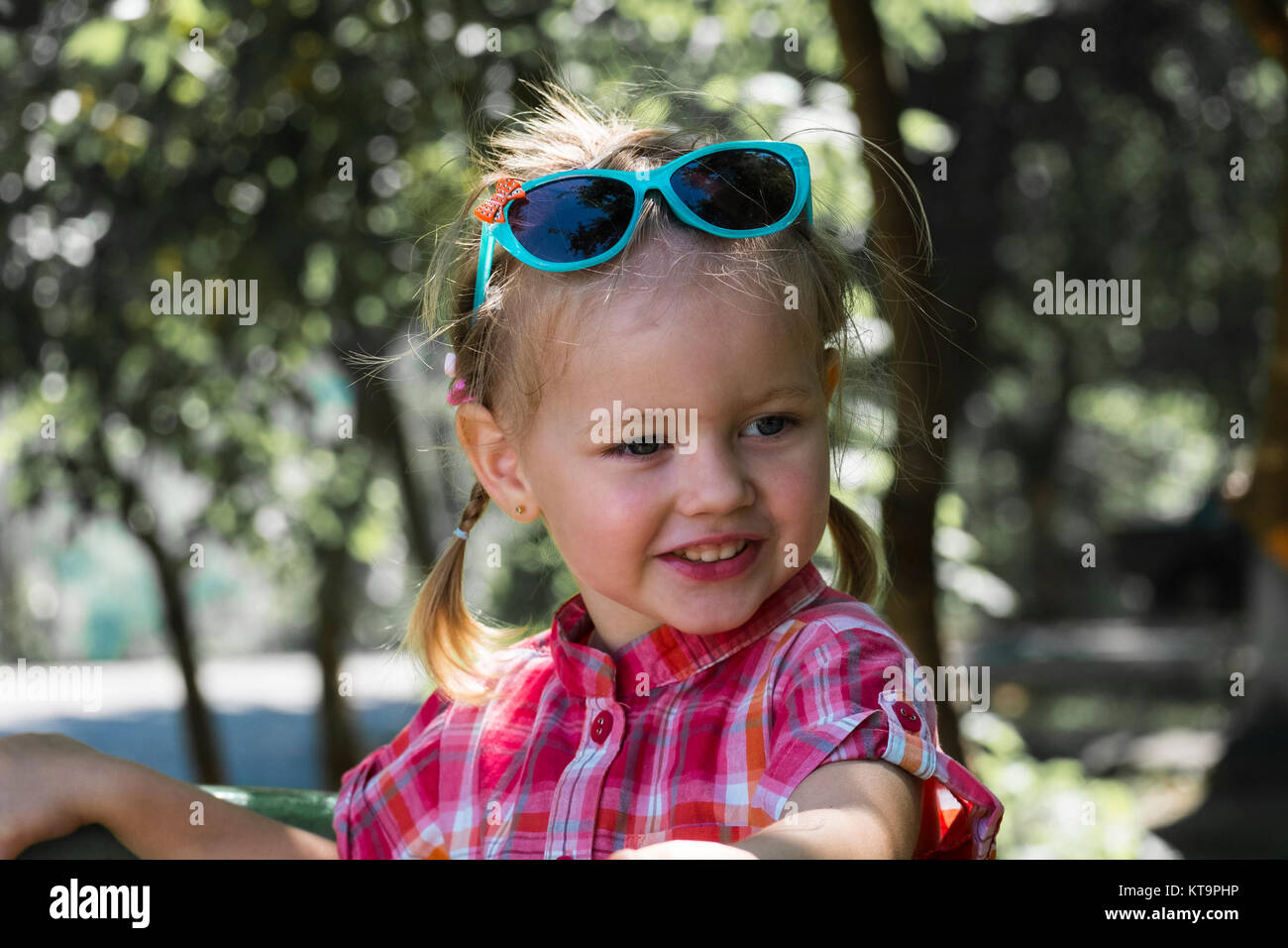 Felice bambina con un divertente sorriso e turchese occhiali da sole sulla  sua testa Foto stock - Alamy