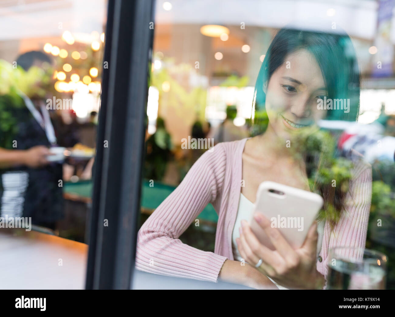 Donna che utilizza il cellulare per on-line all'interno del ristorante Foto Stock