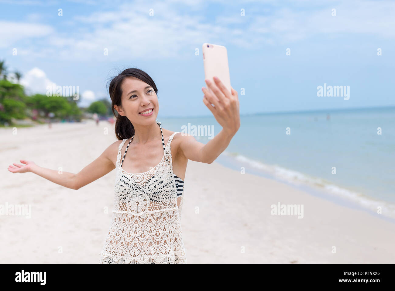 Donna prendendo selfie dal telefono cellulare in spiaggia Foto Stock