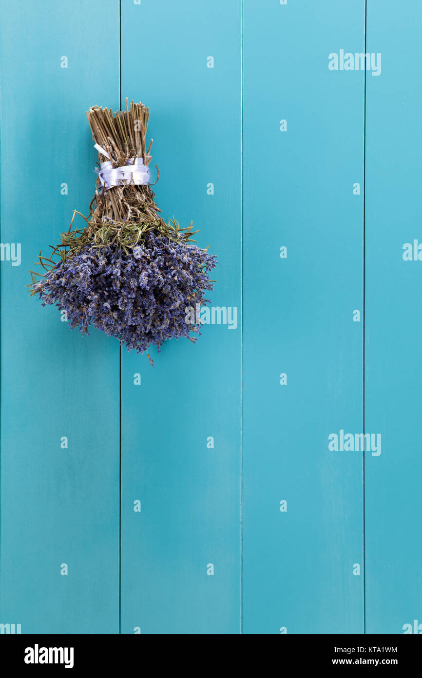 Ein Bündel Lavendel hängt zum Trocknen auf einer mediterranbllauen Holzwand Foto Stock