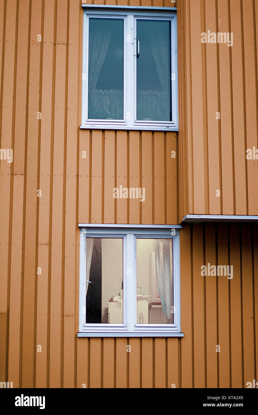 Parete arancione casa in legno due finestre bianche Foto Stock