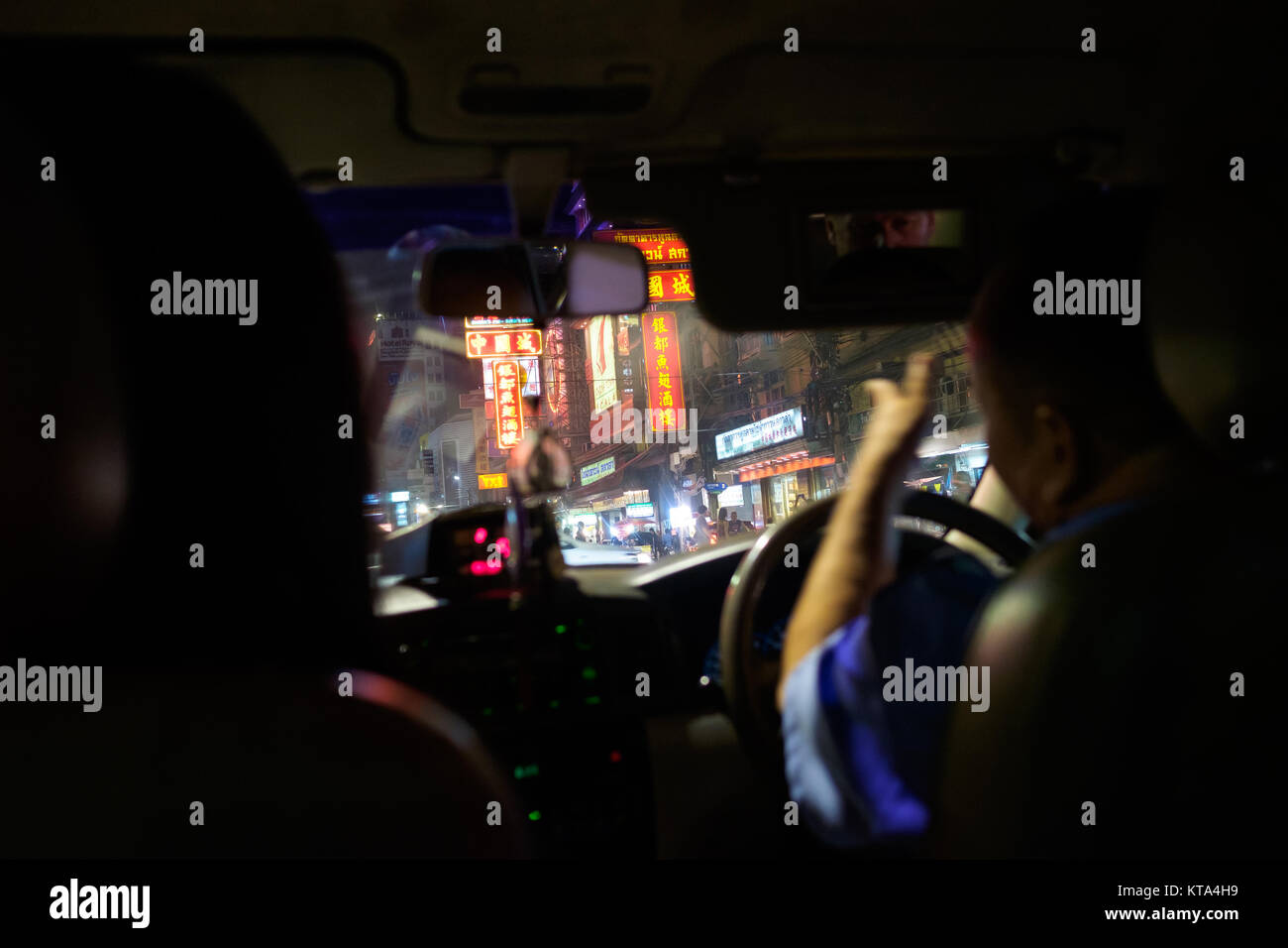 Taxi a Chinatown, Bangkok. Un passeggero si riflette nel driver mirror del driver, gli spostamenti verso le insegne al neon che la linea street Foto Stock