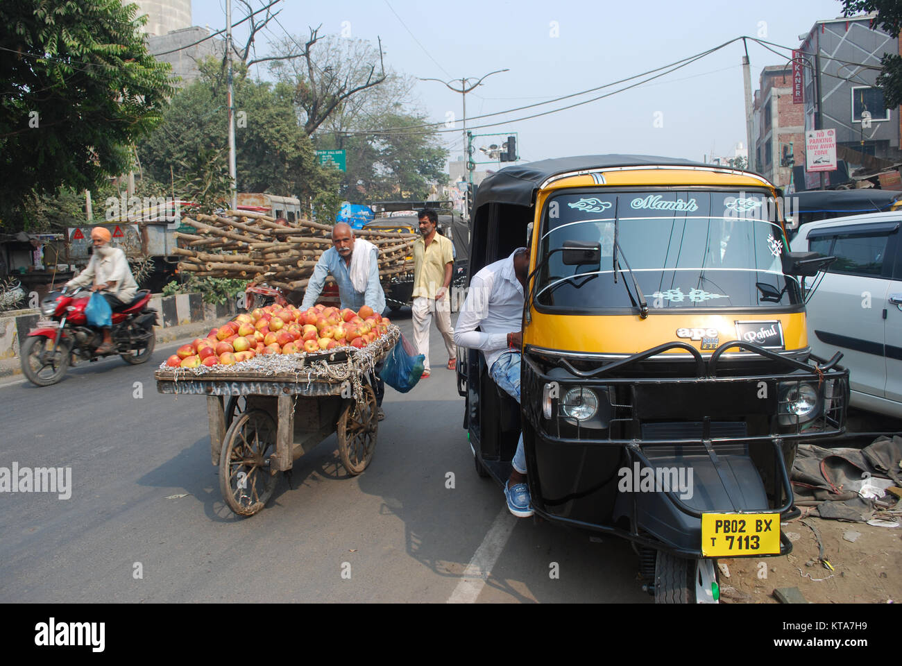 Un Tuk Tuk e un venditore di frutta su una strada trafficata in una scena di strada di Amritsar Punjab, India Foto Stock