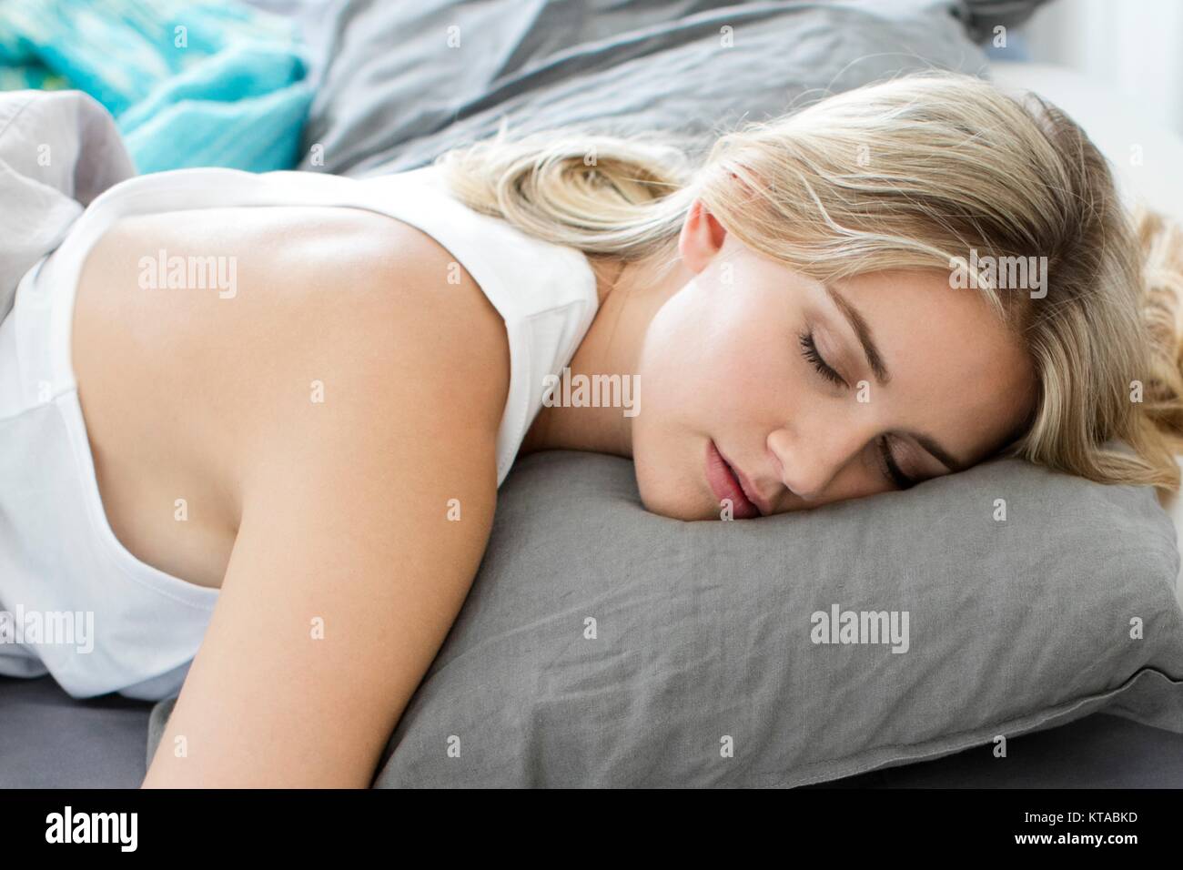 Giovane donna addormentata nel letto. Foto Stock