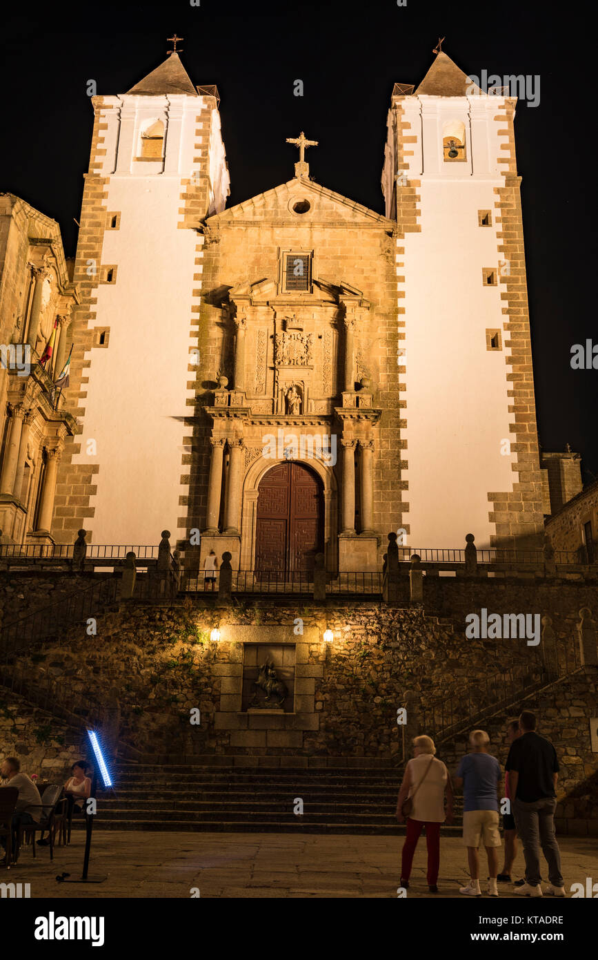 I turisti di notte, guardano il illuminato torri gemelle della chiesa di San Francisco Javier in Caceres, Spagna Foto Stock