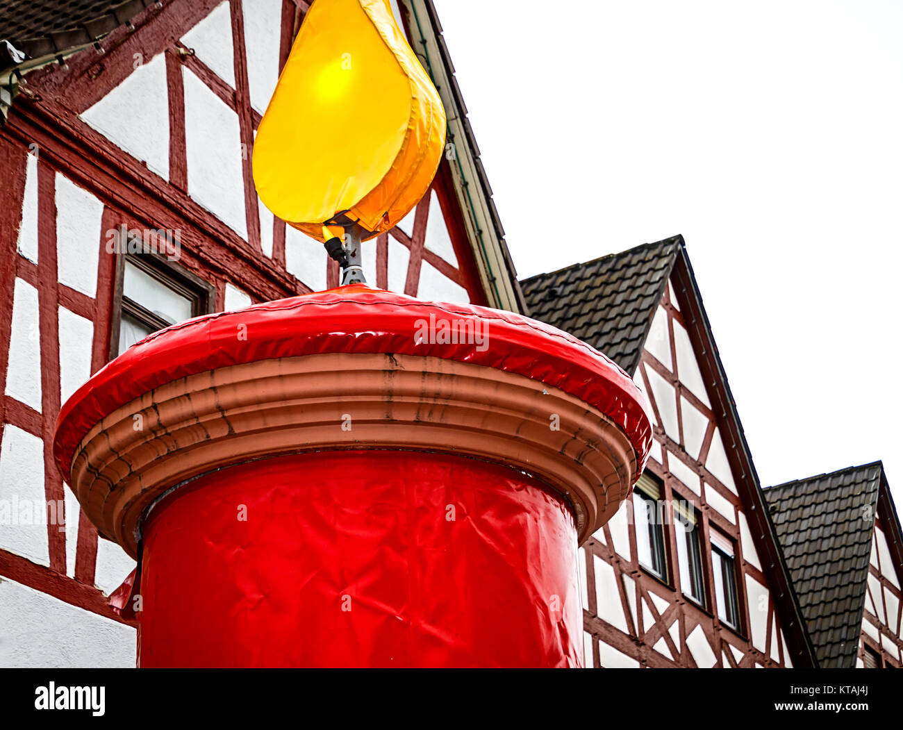 Enorme red christmas candle di fronte Hessian semi-case con travi di legno in un piccolo villaggio Foto Stock