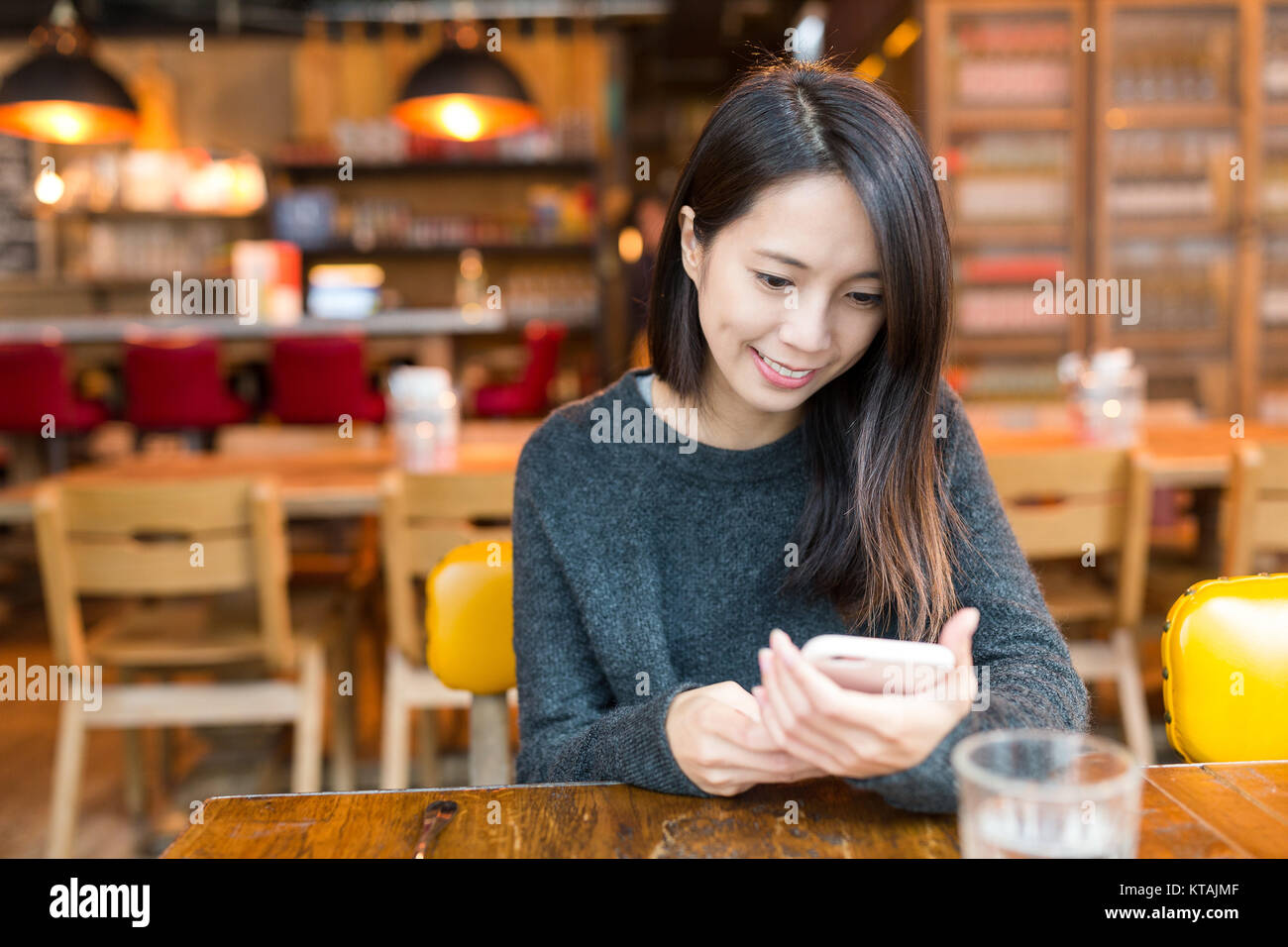 Donna che utilizza il telefono cellulare nel ristorante Foto Stock