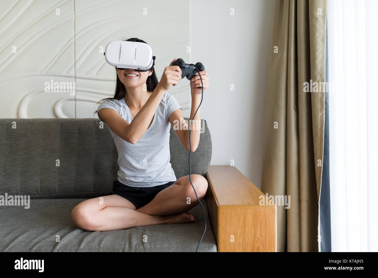 La donna gioca con la realtà virtuale e seduto sul divano Foto Stock