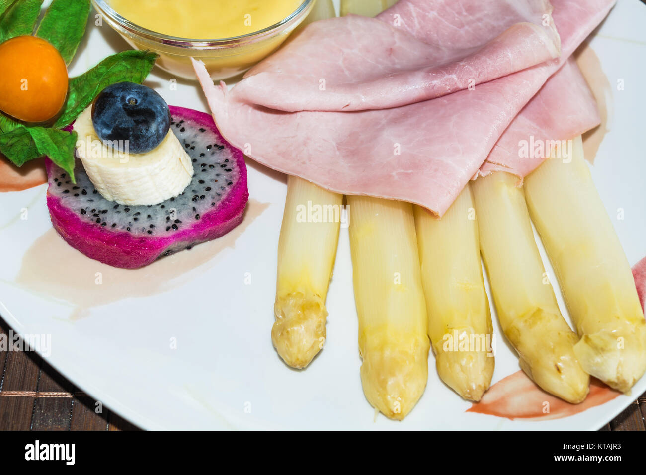 Einfaches Spargelgericht mit gekochten Schinken und Sosse garniert auf einem weissen Teller. Foto Stock