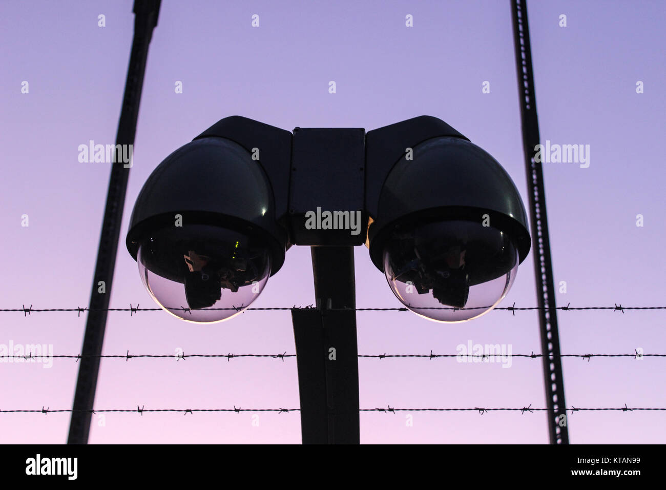 Moderna fotocamera di sorveglianza con barbwire al tramonto e all'alba Foto Stock