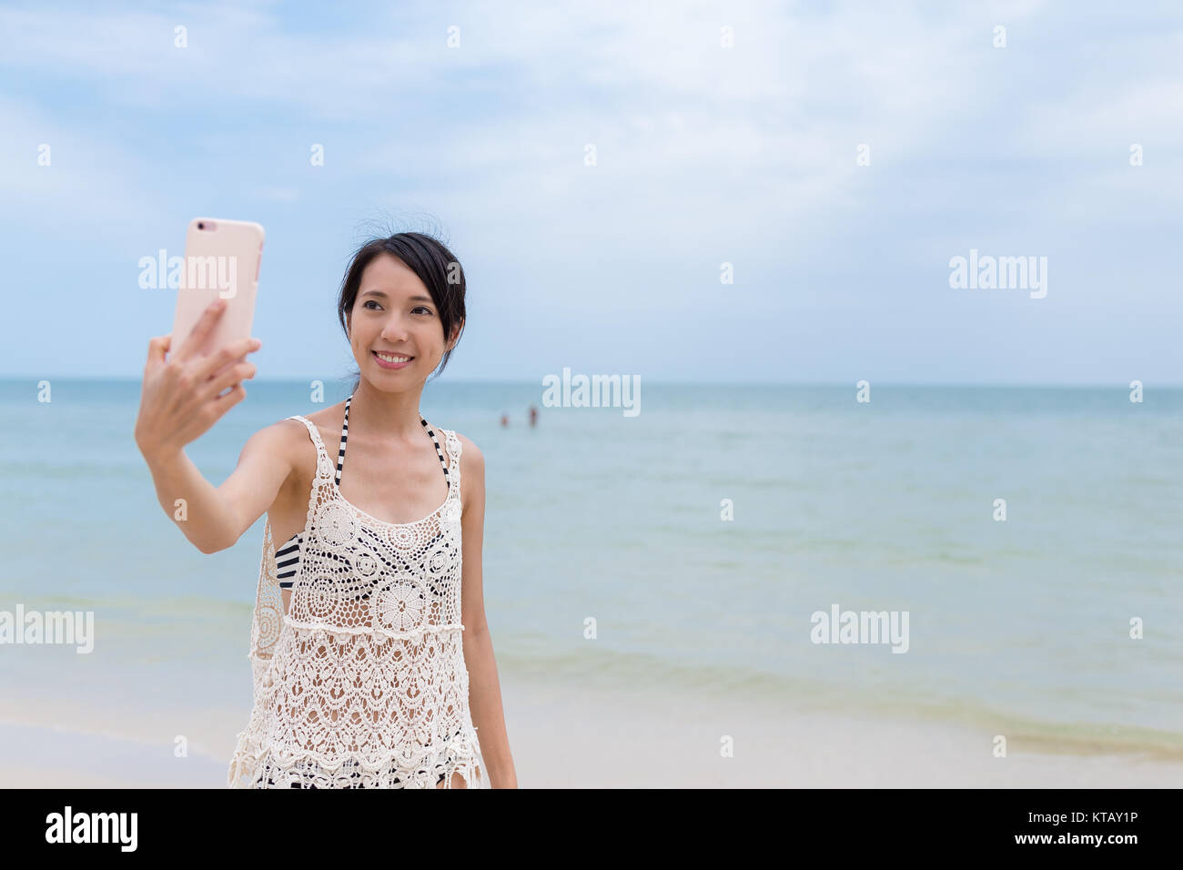 Donna prendendo foto dal telefono cellulare in spiaggia di sabbia Foto Stock