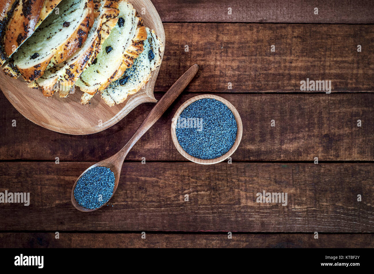 Semi di papavero in una ciotola di legno e un cucchiaio su una superficie di colore marrone Foto Stock