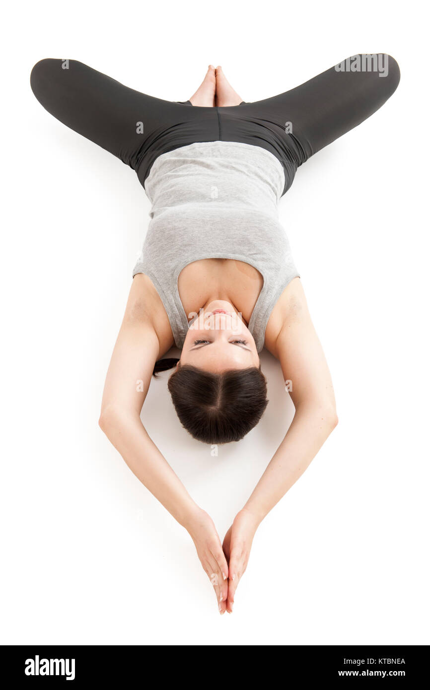 Erhöhte Ganzkörper-Ansicht einer auf dem Rücken liegenden jungen Frau in der Yogaposition 'liegender Schmetterling' (supta baddha konasana) auf weißem Hintergrund. Foto Stock