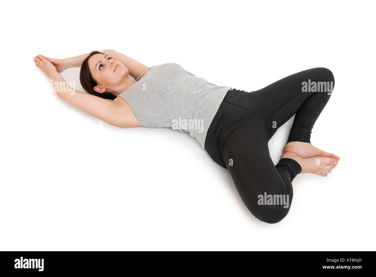 Erhöhte Ganzkörper-Ansicht einer auf dem Rücken liegenden jungen Frau in der Yogaposition 'liegender Schmetterling' (supta baddha konasana) auf weißem Hintergrund. Foto Stock