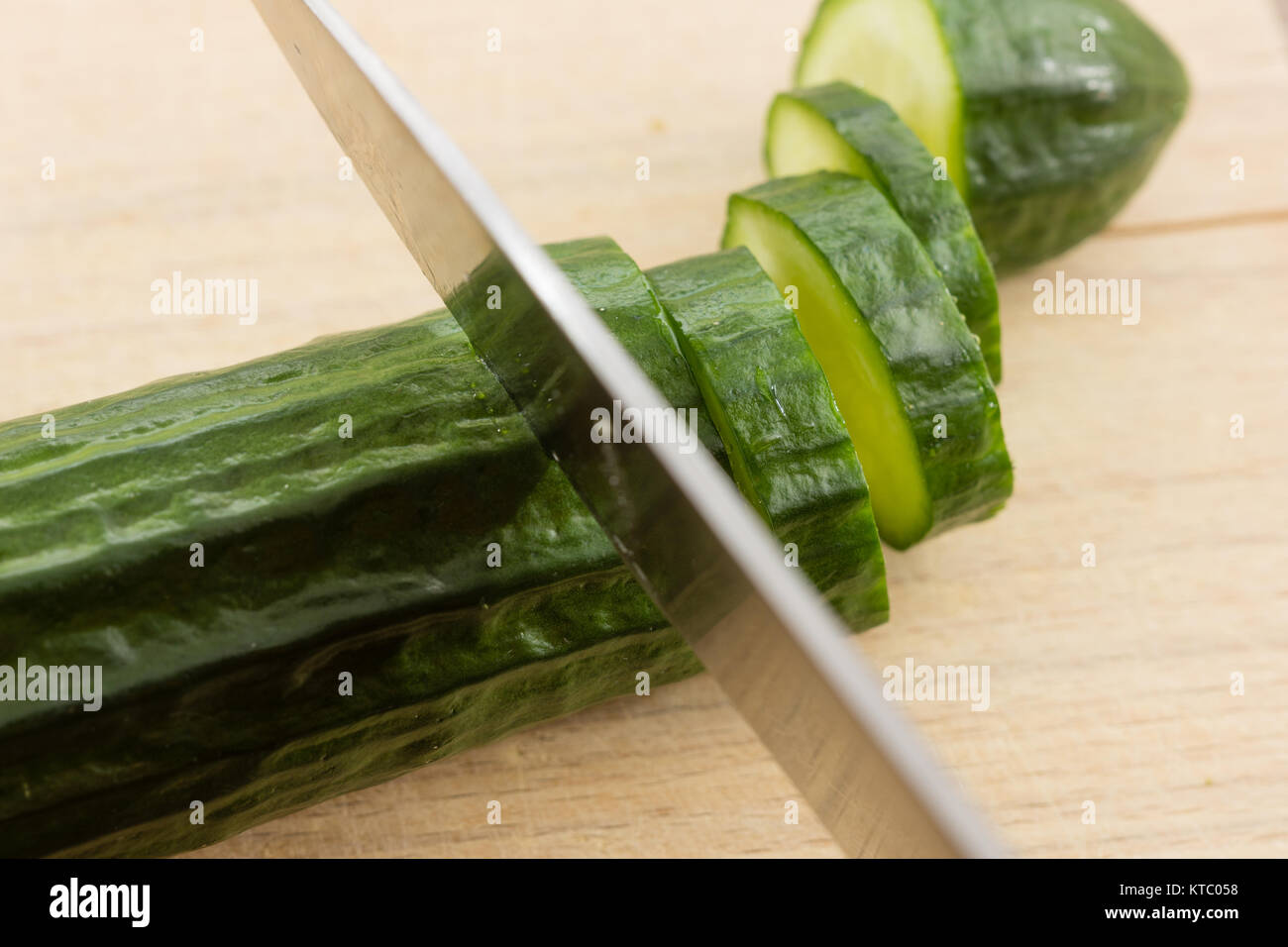 Schneiden einer Salatgurke auf einem Holzbrett Foto Stock