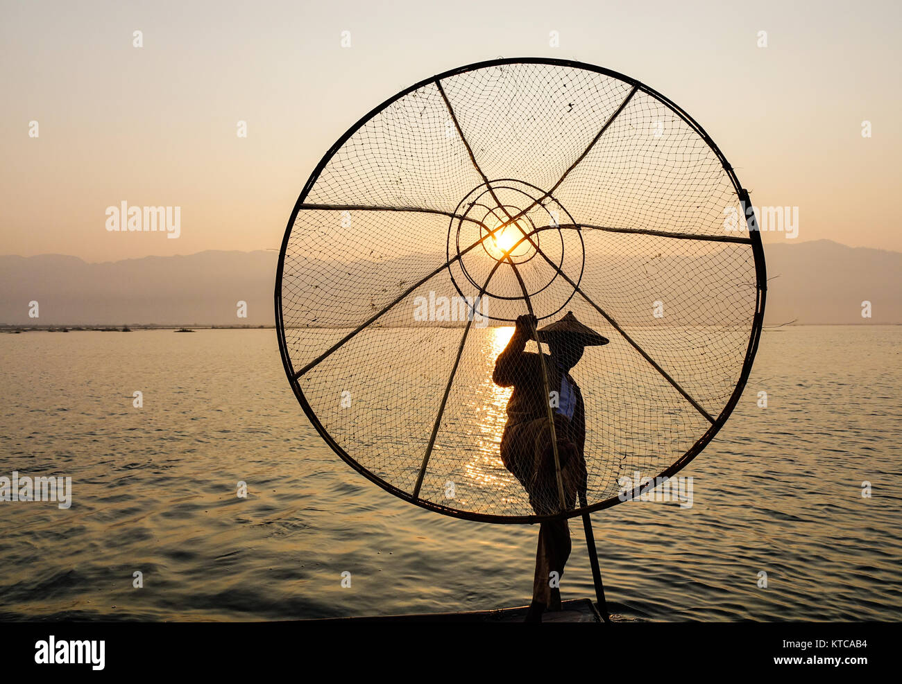 Un pescatore Intha la cattura di pesce sul Lago Inle a sunrise in Shan, Myanmar. Il Lago Inle regione è uno di Myanmar la maggior parte delle destinazioni anticipato e al Foto Stock