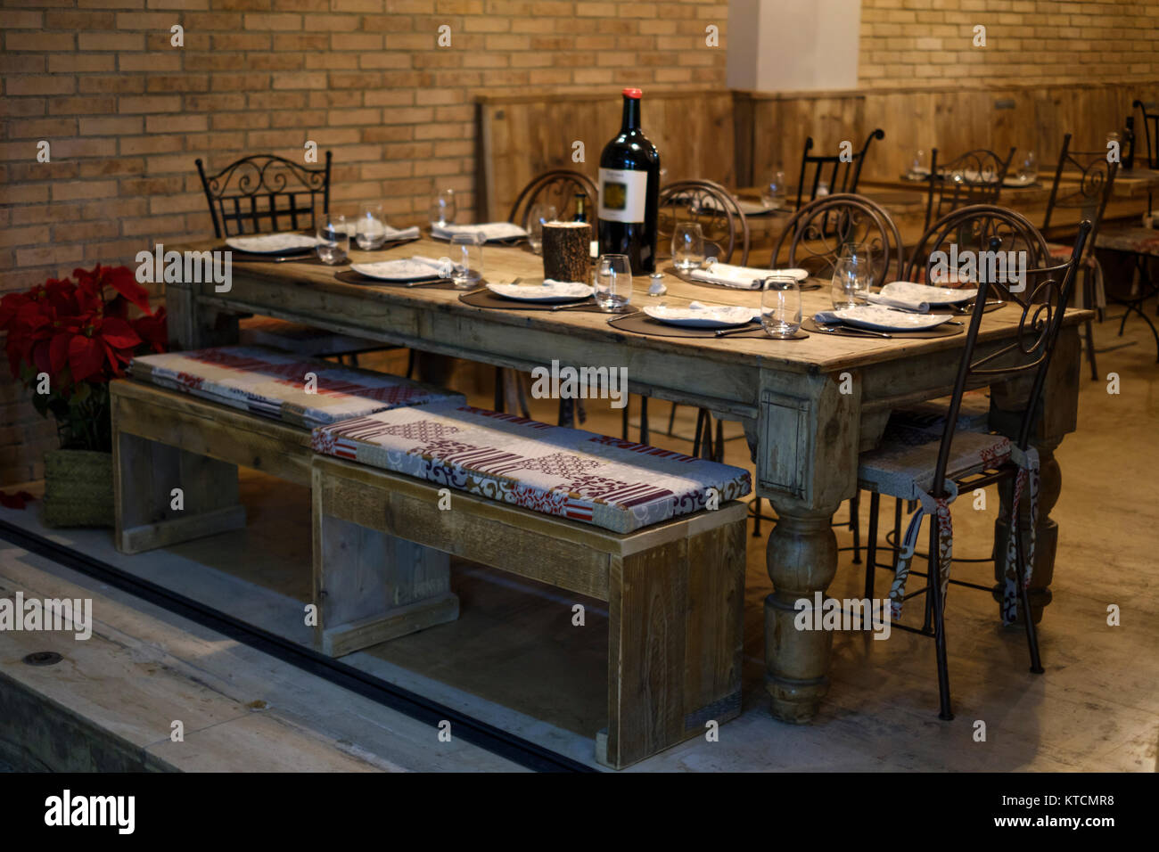 Vecchio solido tavolo di legno in un ristorante ben coperta e dotata di stoviglie e una bottiglia grande di vino Foto Stock