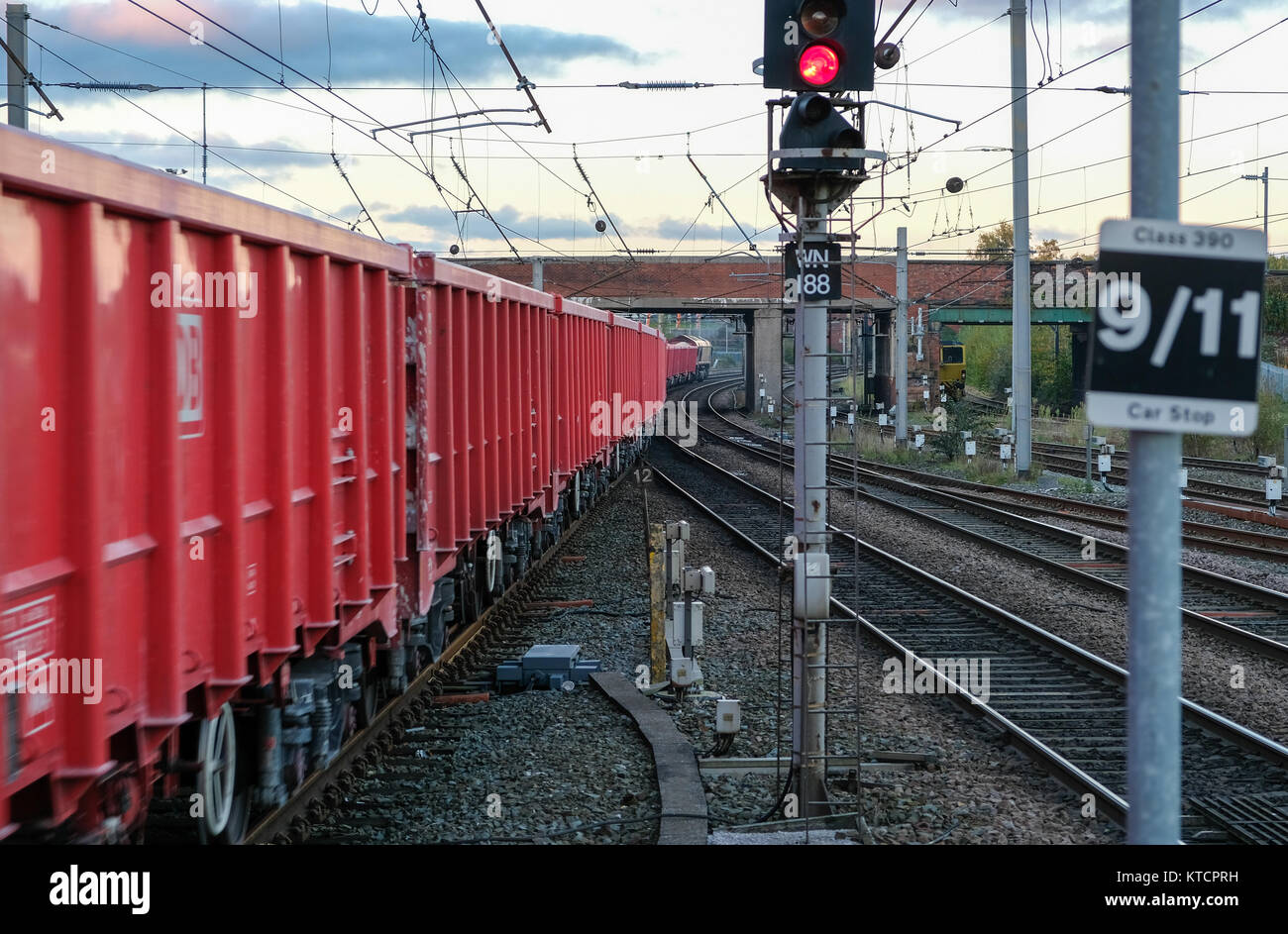Vagoni ferroviari merci rossi sui binari con luce di segnalazione al crepuscolo, trasporto e concetto industriale Foto Stock