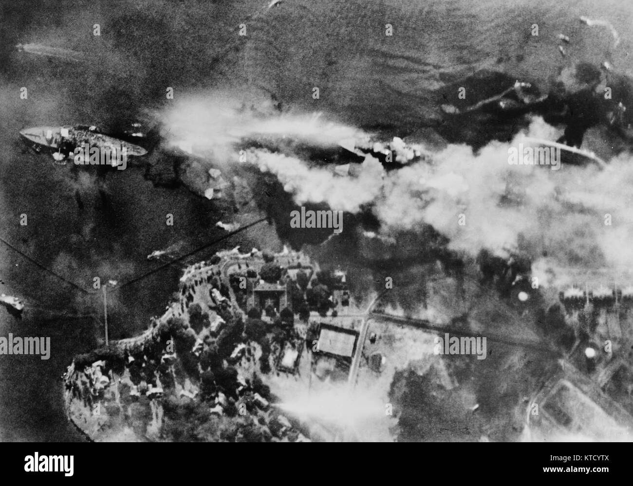 Attacco di Pearl Harbor, 7 Dicembre 1941 - Verticale vista aerea della corazzata fila, accanto a Ford Island, presto dopo la USS Arizona è stato colpito da bombe e avanti la sua riviste esploso. Fotografato da un aereo giapponese. Le navi si vede sono (da sinistra a destra): USS Nevada; USS Arizona (burning intensamente) con USS Vestal ormeggiate; fuoribordo USS Tennessee con USS West Virginia ormeggiate; fuoribordo e USS Maryland con USS Oklahoma ribaltati a fianco. Il fumo proveniente da bomba colpisce su Vestal e West Virginia è anche visibile. Foto Stock