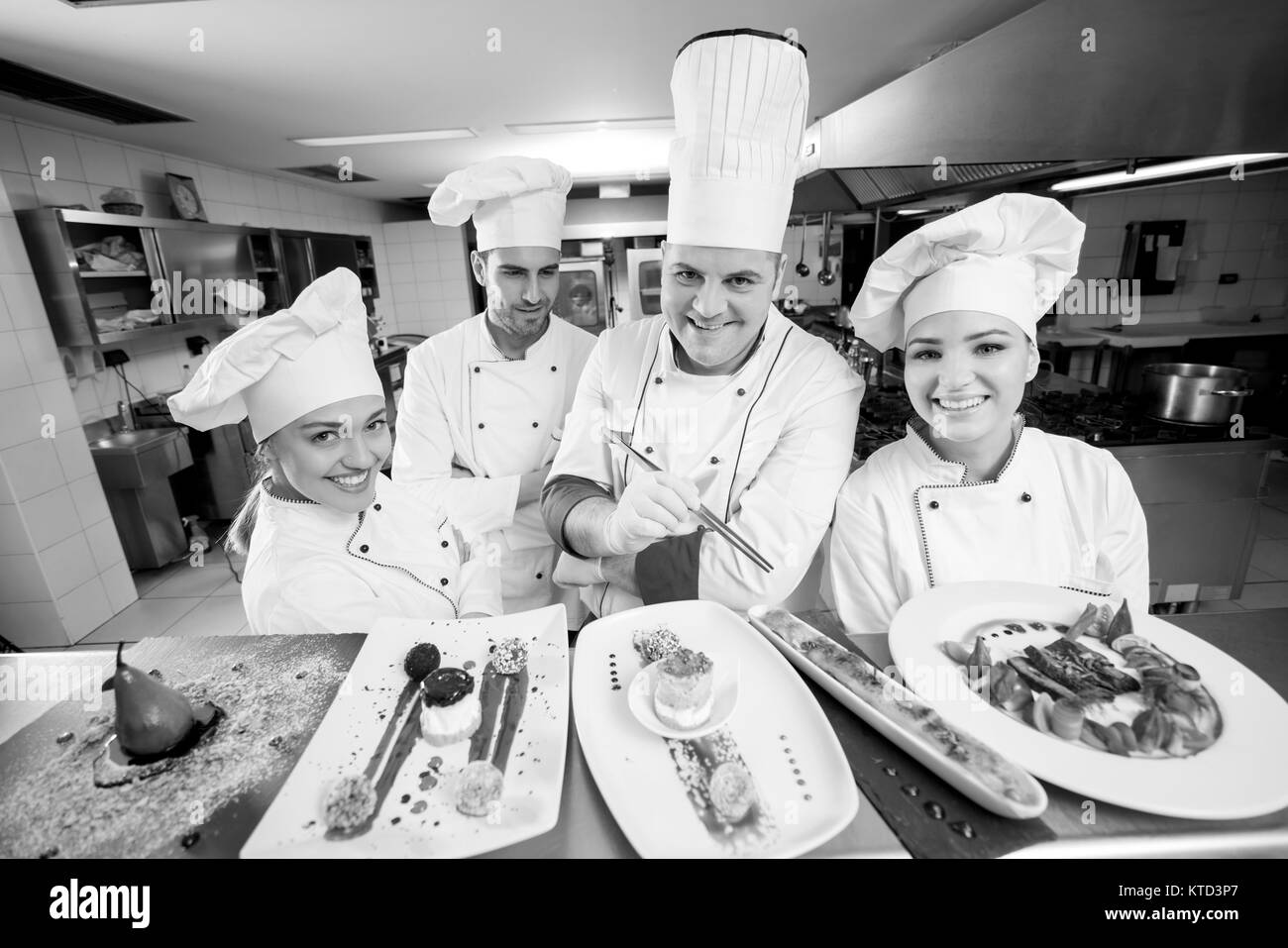 Chef di cucina con giovani apprendisti rendendo deserti Foto Stock