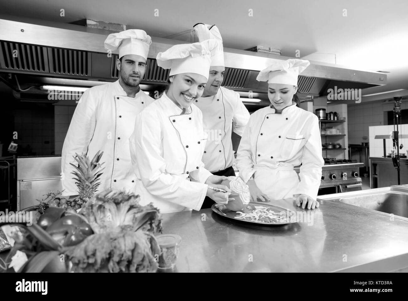 Chef di cucina con giovani apprendisti, insegnamento per rendere decorativo cesto di frutta Foto Stock