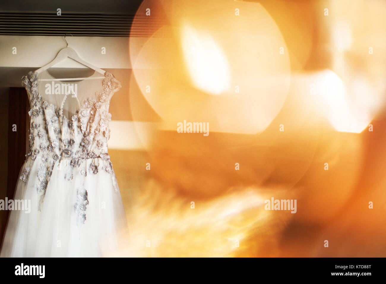 Abito da sposa appeso al muro in camera con evidenza. Foto Stock