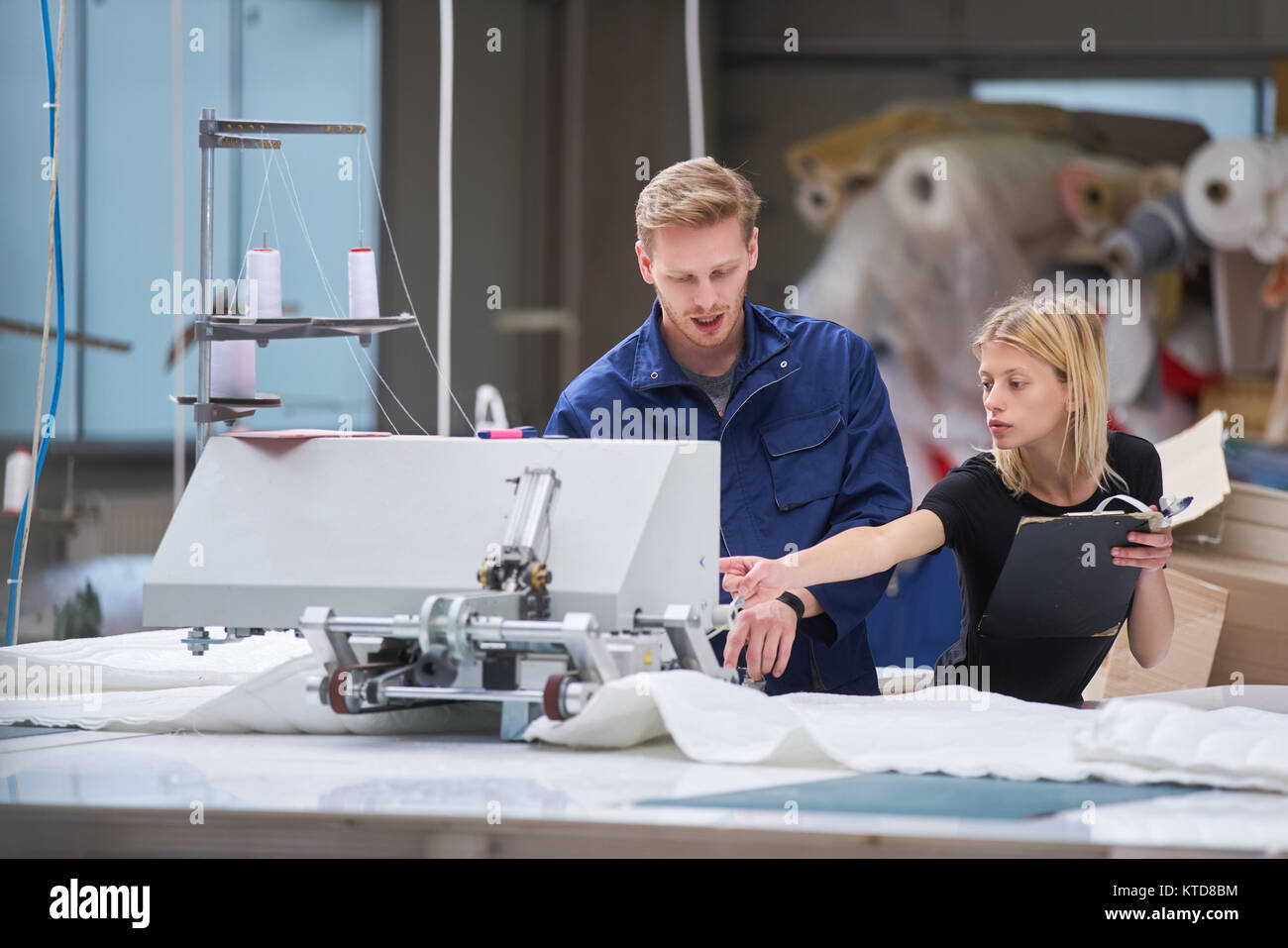 Sarta è nuovo assegnato ad una macchina in una fabbrica tessile, il caposquadra spiega qualcosa Foto Stock