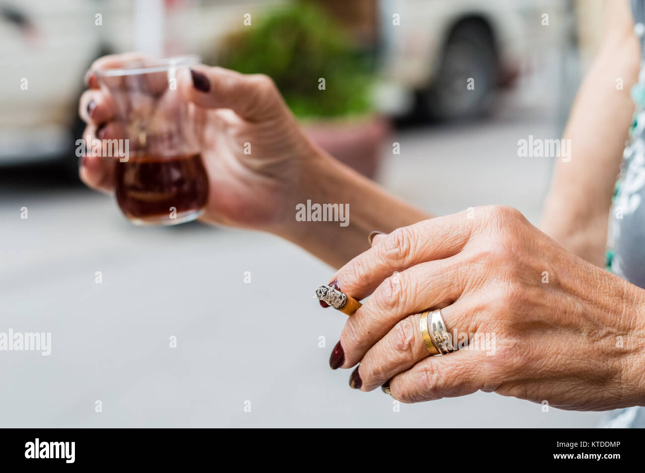 Vecchia donna mani tenendo un bicchiere di tè turco e sigaretta. Concetto di tossicodipendenza. Foto Stock