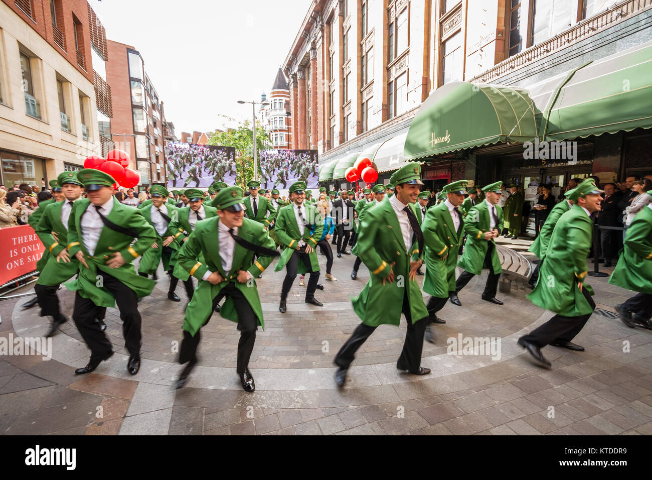 Harrods Summer Sale viene lanciato con un uomo verde flash mob dance stravaganza per le code di clienti in attesa. Foto Stock