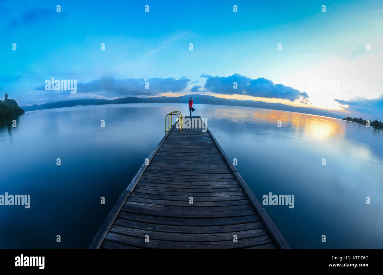 Pratica Yoga di freschi la mattina presto accanto al lago. Foto Stock