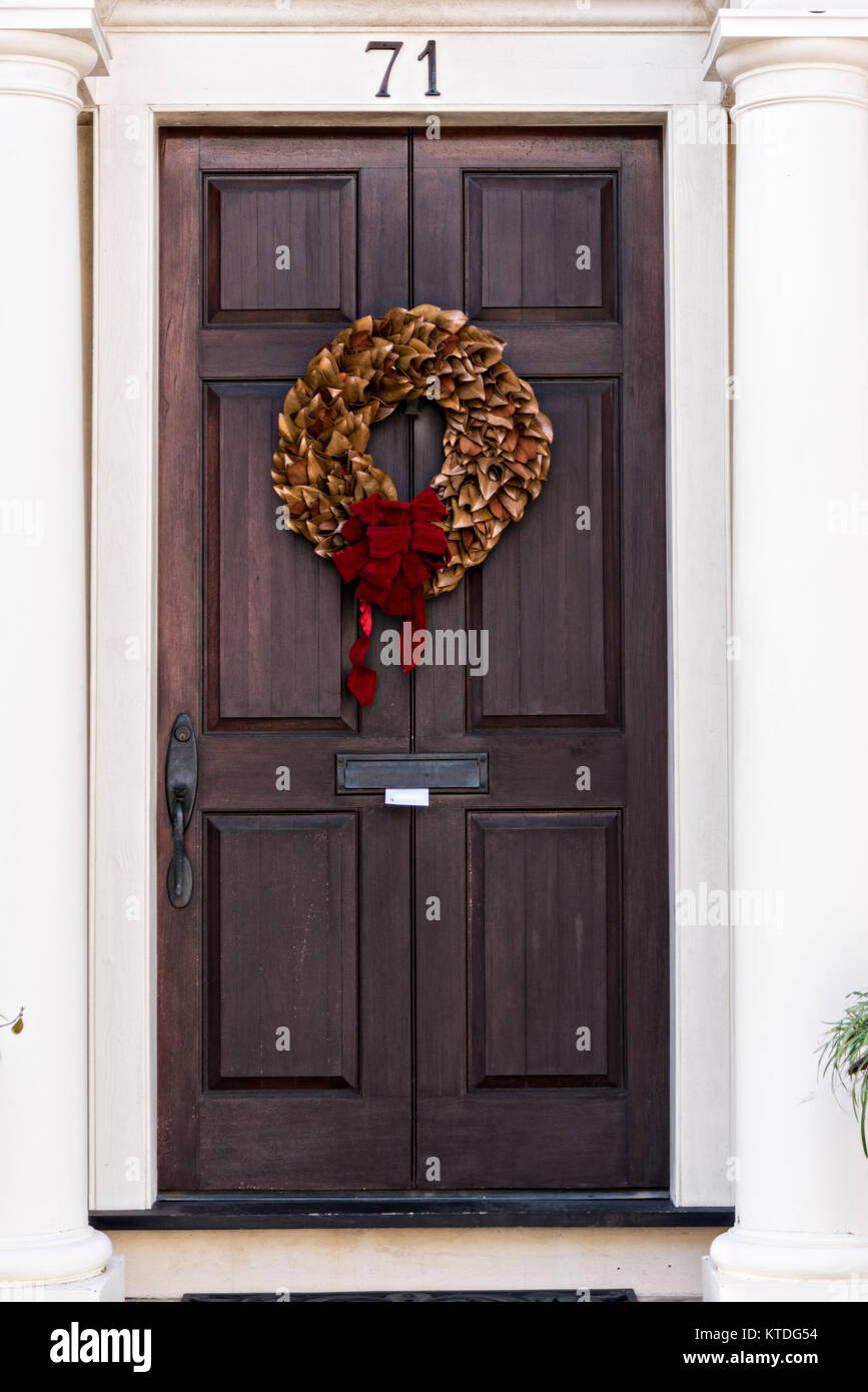 Una foglia di Magnolia ghirlanda di Natale pende da una porta di legno su una storica casa lungo King Street a Charleston, Sc. Foto Stock