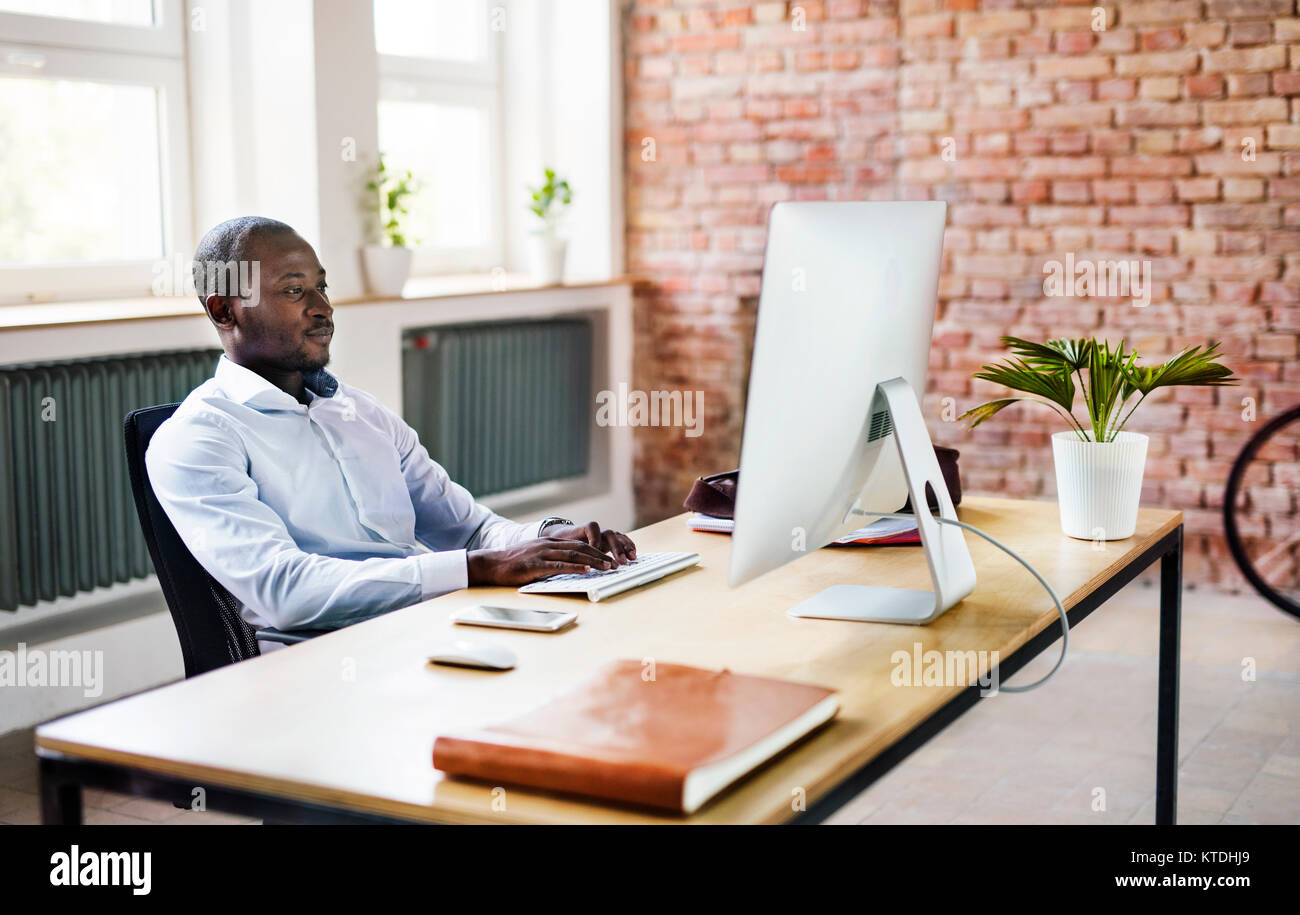 Imprenditore utilizzando computer presso la scrivania in ufficio Foto Stock