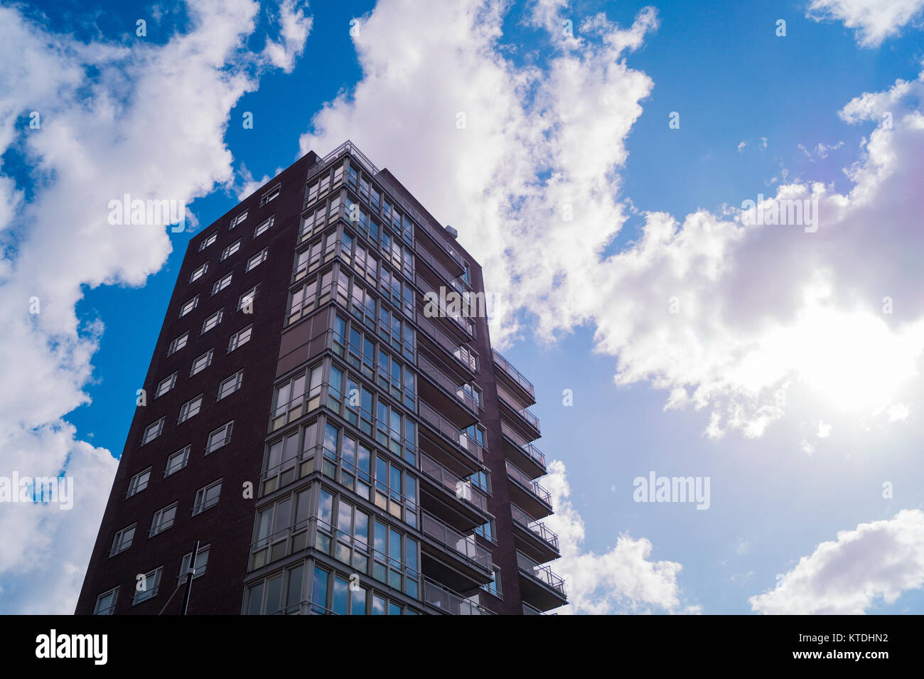 un alto grattacielo moderno solo alla luce del sole con bianco nuvole e un cielo blu come sfondo Foto Stock