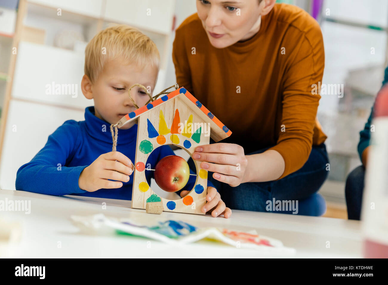 Bambino e pre-insegnante della scuola la costruzione di una tabella di uccelli nella scuola materna Foto Stock