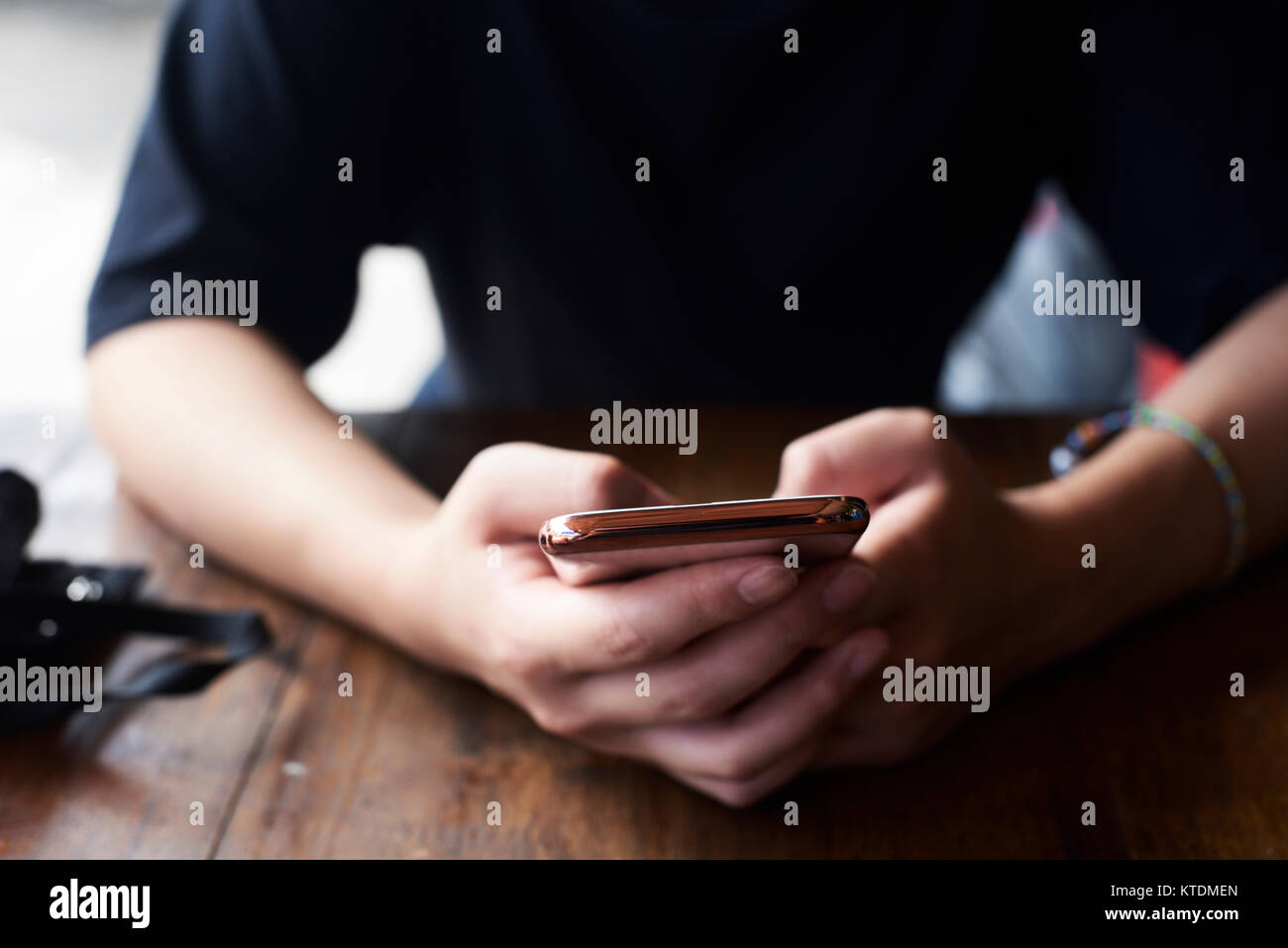 Asian mani femminili di close-up utilizzando il suo telefono su un tavolo di legno. Chiang Mai, Thailandia. Foto Stock