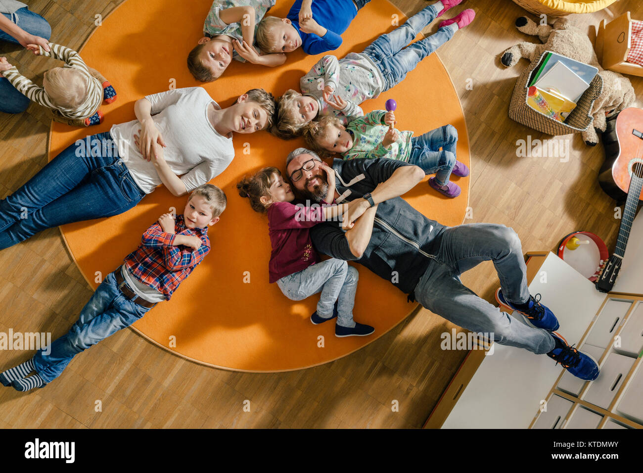 I bambini e gli insegnanti che giace sul tappeto in kindergarten Foto Stock