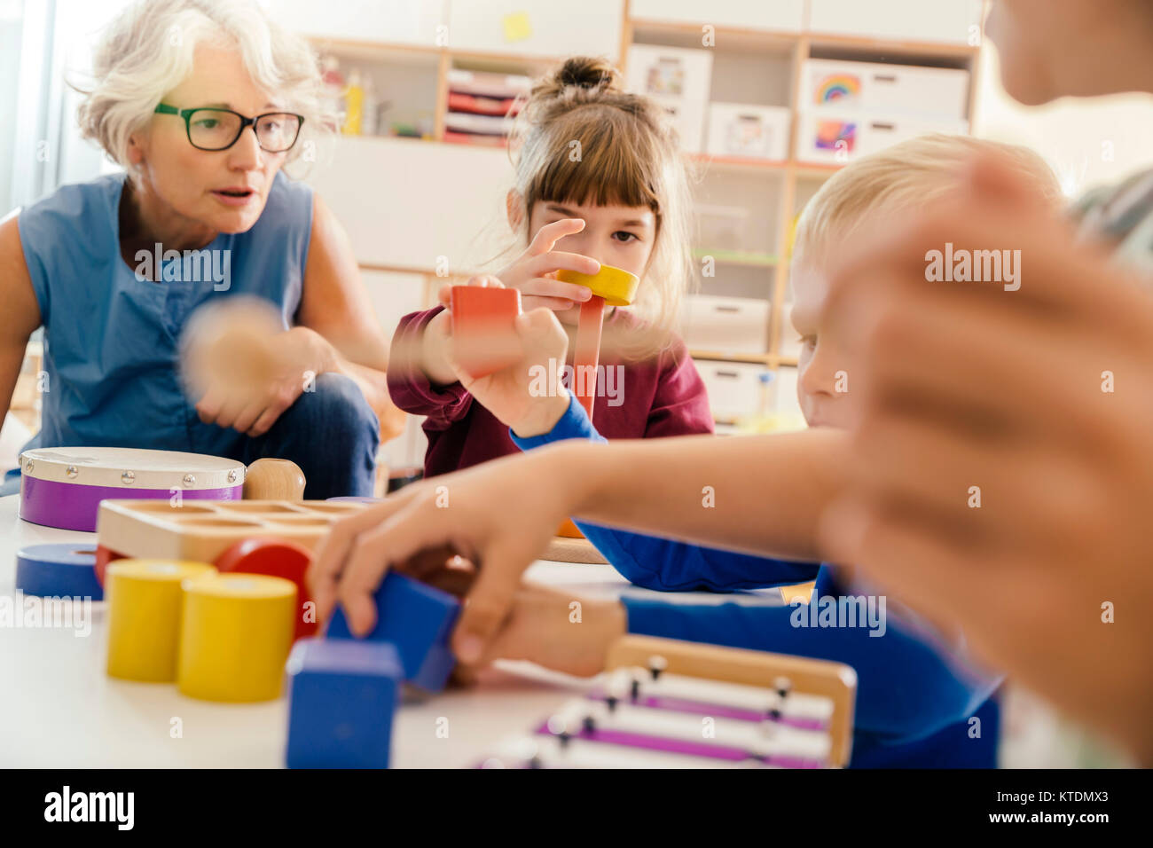 I bambini e il Maestro a giocare con gli strumenti musicali e giocattoli in kindergarten Foto Stock