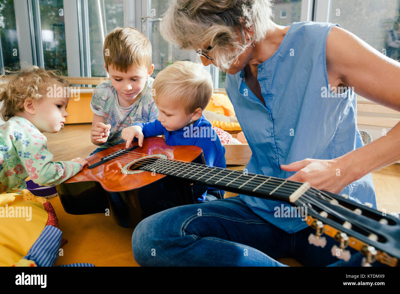 Pre-insegnante della scuola che mostra una chitarra per i bambini in una scuola materna Foto Stock