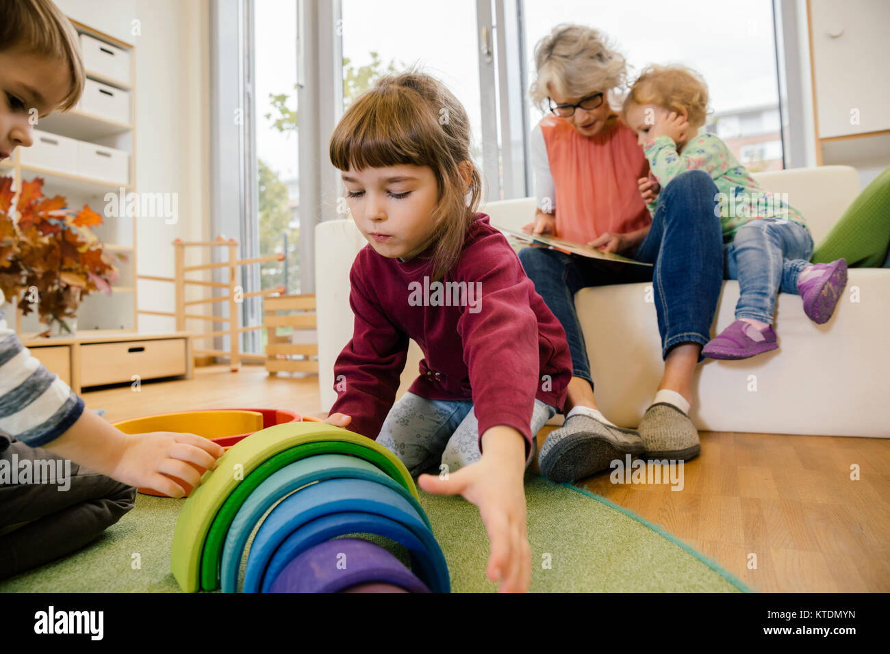 Bambini che giocano e la lettura con insegnante in una scuola materna Foto Stock