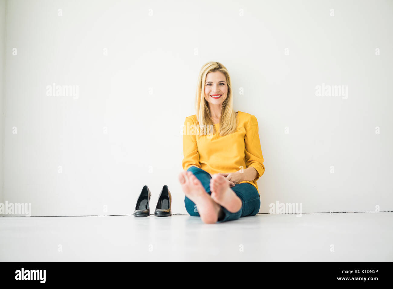 Rilassato sorridente donna seduta sul pavimento Foto Stock
