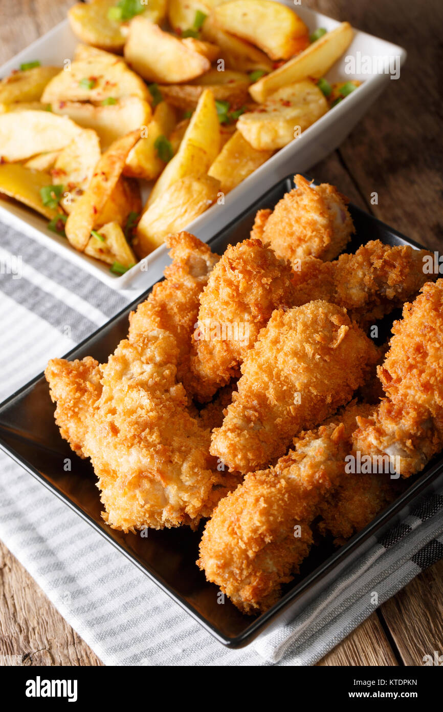 Alette di pollo fritte in panatura e patata vicino sul piano verticale. Foto Stock